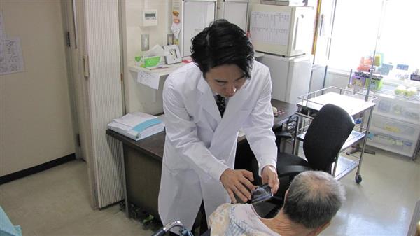 患者の皮膚の患部をスマートフォンで撮影する医師の物部真一郎氏（左）